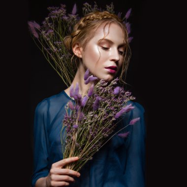 Hafif bir makyaj, saç modeli örgüler, kuru çiçekler, mavi elbise şeklinde güzel kızla. Güzellik.