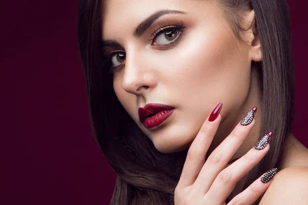 Pretty girl with unusual hairstyle, bright makeup, red lips and manicure design. Beauty face. Art nails.