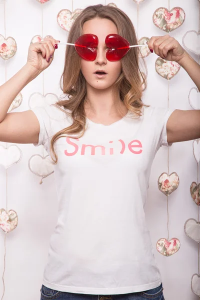 Día de San Valentín. Divertida mujer hermosa sosteniendo caramelos en forma de corazón —  Fotos de Stock