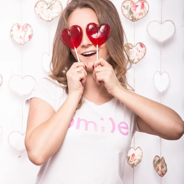 Día de San Valentín. Divertida mujer hermosa sosteniendo caramelos en forma de corazón —  Fotos de Stock