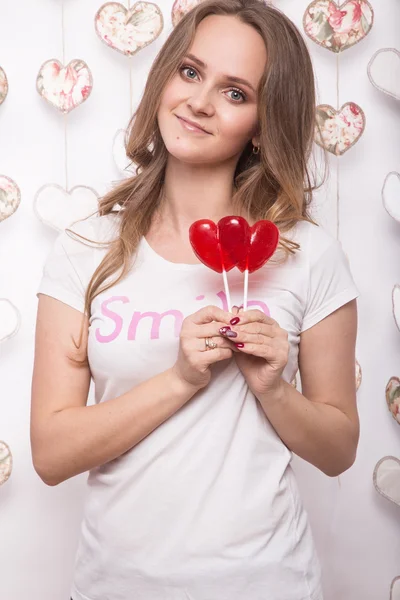 Día de San Valentín. Divertida mujer hermosa sosteniendo caramelos en forma de corazón —  Fotos de Stock