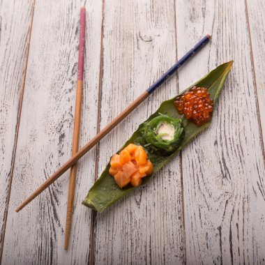 Yaratıcı suşi Japon yemekleri, somon, chuka salata ve havyar bambu bir parçası üzerinde ayarla