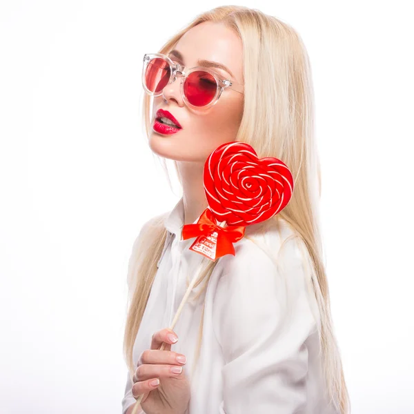 Portrait of Beautiful blond woman with bright makeup and red candy heart in hand. valentines day — Stock Photo, Image