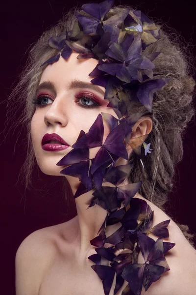 Creative fashionable image, girl with a bright make-up and purple plant on her face. — Stock Photo, Image