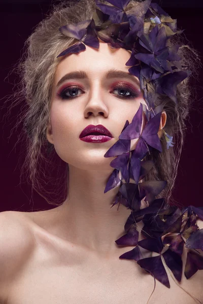 Imagen creativa de moda, chica con un maquillaje brillante y planta púrpura en su cara . — Foto de Stock