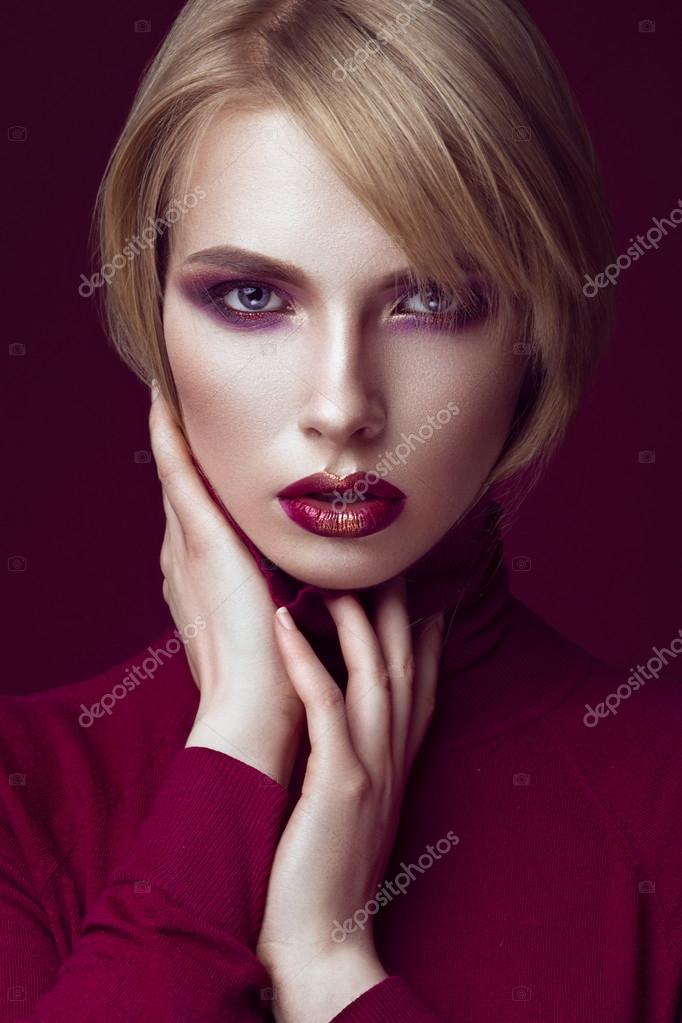 Beautiful blonde woman in a red sweater with bright makeup and