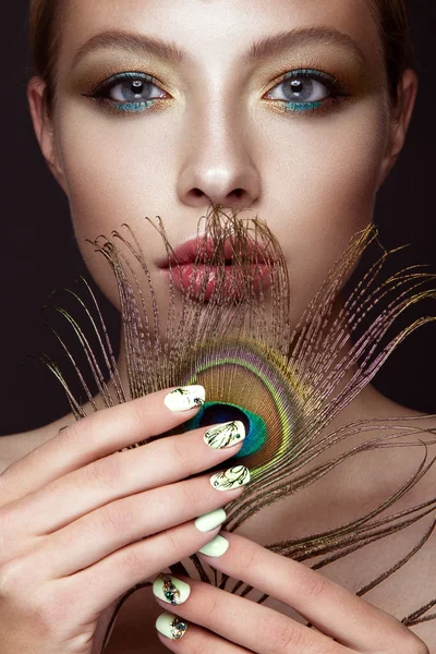 Hermosa chica con maquillaje brillante, diseño de manicura y pluma de pavo real en su cara. Clavos de arte . — Foto de Stock