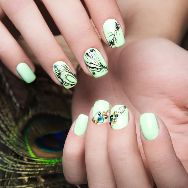 Art design manicure  with peacock feather on female hands. Close-up. Fashion nails.