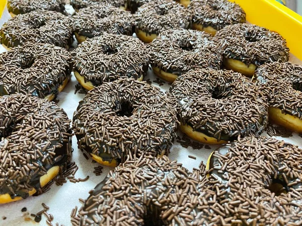 초콜릿 쌀이나 초콜릿에 노란색 쟁반에 도넛을 뿌린다 — 스톡 사진