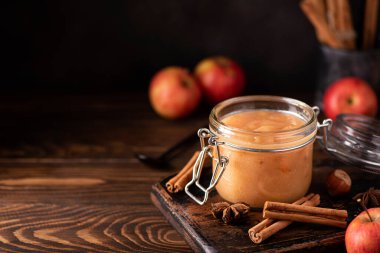 Ev yapımı elma reçeli ve ahşap bir masada cam bir kavanozda tarçın.