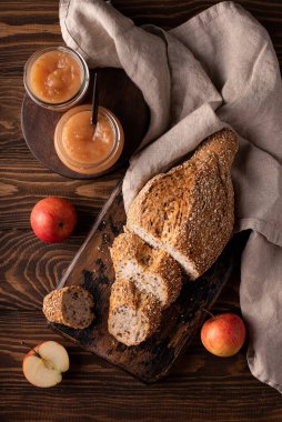 Tarçınlı ev yapımı elma reçeli ve ahşap bir masada dilimlenmiş tahıllı ekmek.
