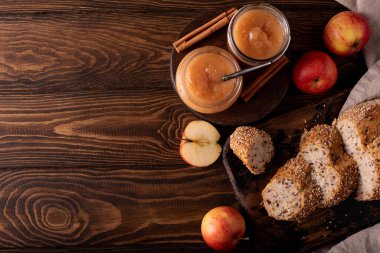 Tarçınlı ev yapımı elma reçeli ve ahşap bir masada dilimlenmiş tahıllı ekmek.