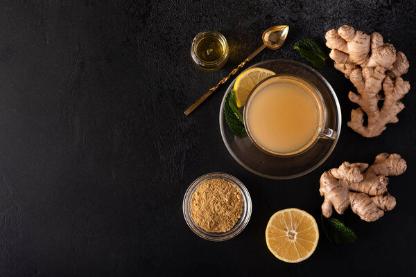 hot vitamin drink made from ground ginger, lemon and honey on a black table, top view