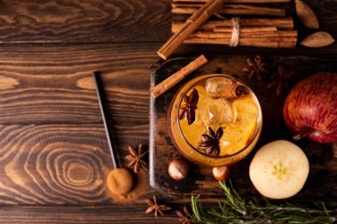 Elma parçalı ev yapımı elma şarabı, tarçın ve baharatlar bir bardakta, üst görünümde.