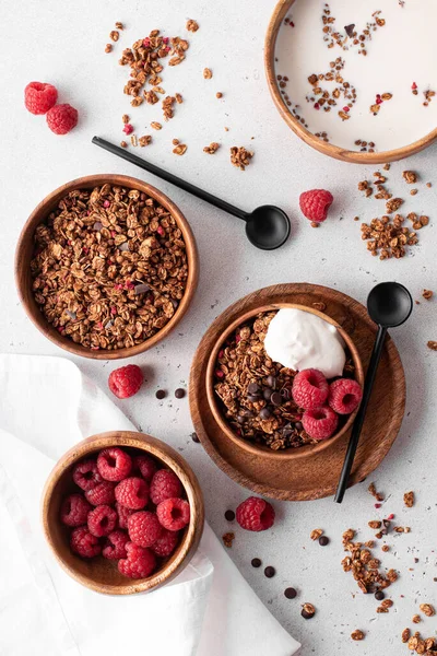 muesli with chocolate, nuts and fresh raspberries in wooden bowls, top view