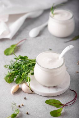 Taze Yunan yoğurdu, cam kavanozlarda bitkiler ve baharatlar var.