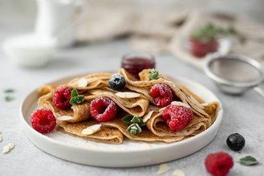 Reçelli krep ve taze böğürtlen, üzerine pudra şekeri serpiştirilmiş, yakın plan.