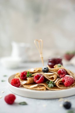 Reçelli krep ve taze böğürtlen, üzerine pudra şekeri serpiştirilmiş, yakın plan.