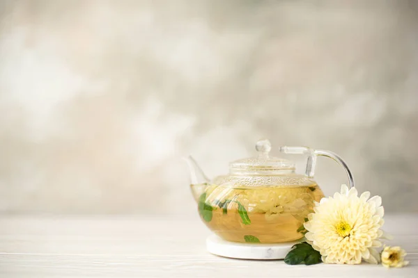 flower herbal tea with chrysanthemum petals in a glass teapot, close-up