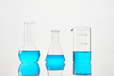 Masanın üzerinde beyaz zemin üzerinde mavi sıvı bulunan laboratuvar camları. Kimyasal analiz. Deneyler için test tüpleri.