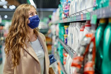 Coronavirus Covid-19 salgını sırasında alışveriş. Yüz maskeli ve lastik eldivenli kadın süpermarketten bir şeyler alıyor..