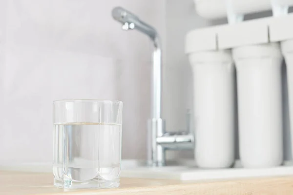 A glass of clean water with osmosis filter in a kitchen interior. Concept Household filtration system.