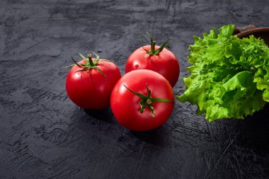 Salata salatalı taze üzüm domatesleri siyah taş arka planda yapraklar. Vejetaryen sebze diyeti. Bitki, domates, aşçılık konsepti.