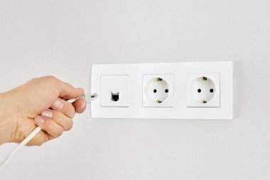 Bir adamın ethernet kablosunu bir duvar prizine takarken yakın plan fotoğrafı..