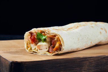 Shawarma sandviçi. Tavuk eti, peynir, sos ve yeşille doldurulmuş taze lavaş rulosu. Geleneksel Doğu atıştırması.
