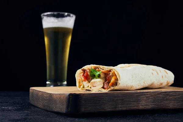 Fast food and Cold light beer. shawarma placed on a wooden board on bar counter. Copy space.