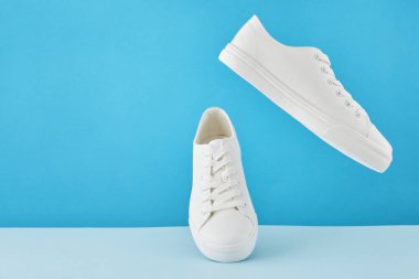 Bir çift şık beyaz spor ayakkabı, Pastel mavi arka planda koşu ayakkabısı..