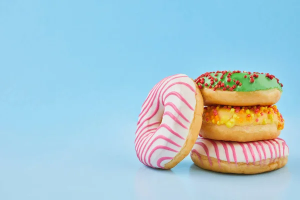 Pastel mavi arka plan üzerine serpiştirilmiş donutlar. Mavi kağıtta tatlı çörekler.