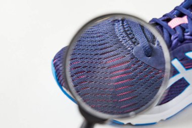 Alıcı, ayakkabılarında büyüteçle kusurları ve makro detayları arıyor. Tarz ve moda ayakkabıları. Nefes alabilen ayakkabıların keşfi.