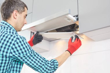 Adam mutfaktaki kaputu onarıyor. Fırın kaputunda yer değiştirme filtresi.