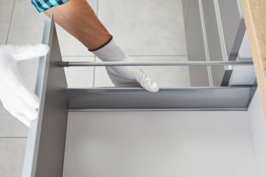 Tamirci toplanıyor ve mutfağa bir çekmece kuruyor. İşçi, kabine çekmecesinin mobilya mekanizmasını tamir ediyor.