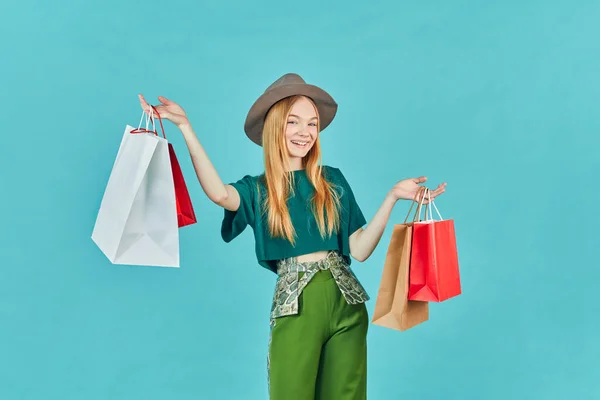 快乐的年轻女人拿着购物袋呆着 漂亮的女孩走购物中心背着许多蓝色背景的好货包 — 图库照片