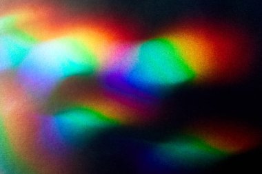 Koyu kaba desenli karton üzerinde parlak renkli bir parıltı. Yumuşak gökkuşağı ışığı. Soyut renkli arkaplan.