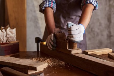 Marangoz, marangozhanedeki ahşap masada ekipmanla çalışıyor. Kadın bir marangozhanede çalışıyor..