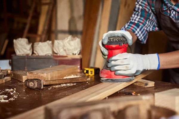 女木匠用砂纸在木工车间或灰色车间中研磨木料 在木工中工作的电砂机 女孩用电动砂子擦亮木板 — 图库照片