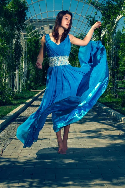 Beautiful woman dancing barefoot in a long blue dress — Stock Photo, Image