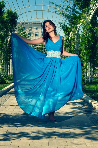 Beautiful woman dancing barefoot in a long blue dress — Stock Photo, Image