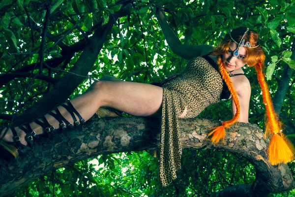 Krásná červená hlava žena sedí na stromě — Stock fotografie
