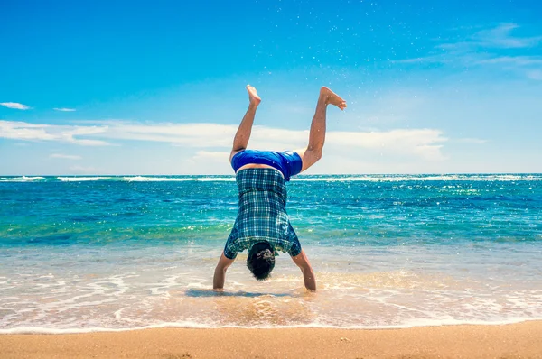 Man doen handstand op het strand Stockafbeelding