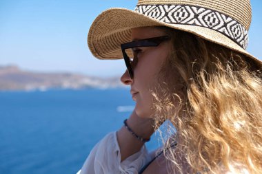 Beyaz gözlüklü, bikinili, hasır şapkalı, tatil köyündeki deniz manzaralı güzel bir kadın.