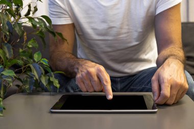 Evde dijital tablet kullanan bir adam var. Çevrimiçi eğitim, çalışma, video çağrısı