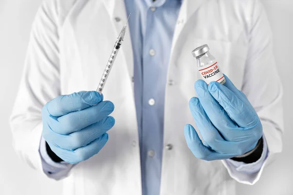Лікар в білому халаті і рукавичках тримає шприц в руці з рідкими вакцинами ампула для вакцинації кованого коронавірусу-19 — стокове фото