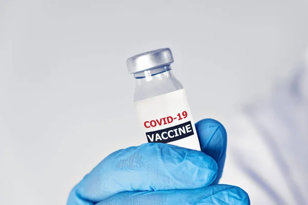 Conceptul de vaccinare cu coronavirus covid-19 în mâna fiolei de vaccin din sticlă. Haină albă și mănuși — Fotografie, imagine de stoc