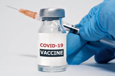 COVID-19 Coronavirus aşısı ve şırınga koruyucu eldivenlerle doktor elinde