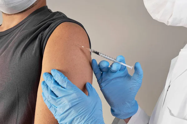 Концепція вакцинації. лікар в рукавичках вакцинація молодого чоловіка шприцом — стокове фото