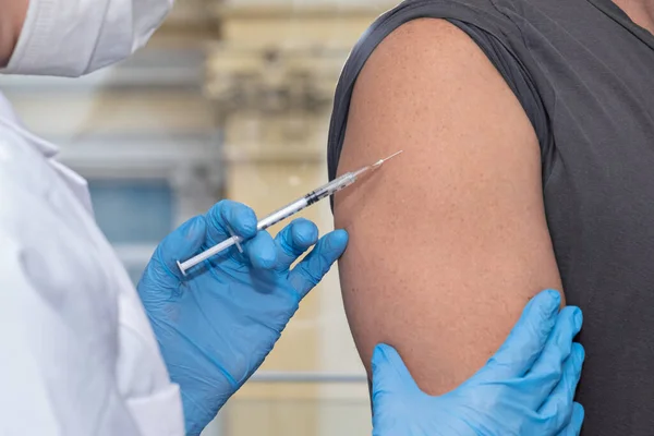 Концепція вакцинації. лікар в рукавичках вакцинація молодого чоловіка шприцом — стокове фото